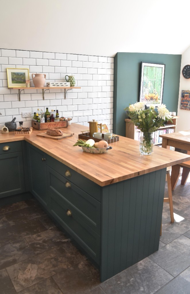 Forest green shaker cabinetry with oak butcher block and brass hardware